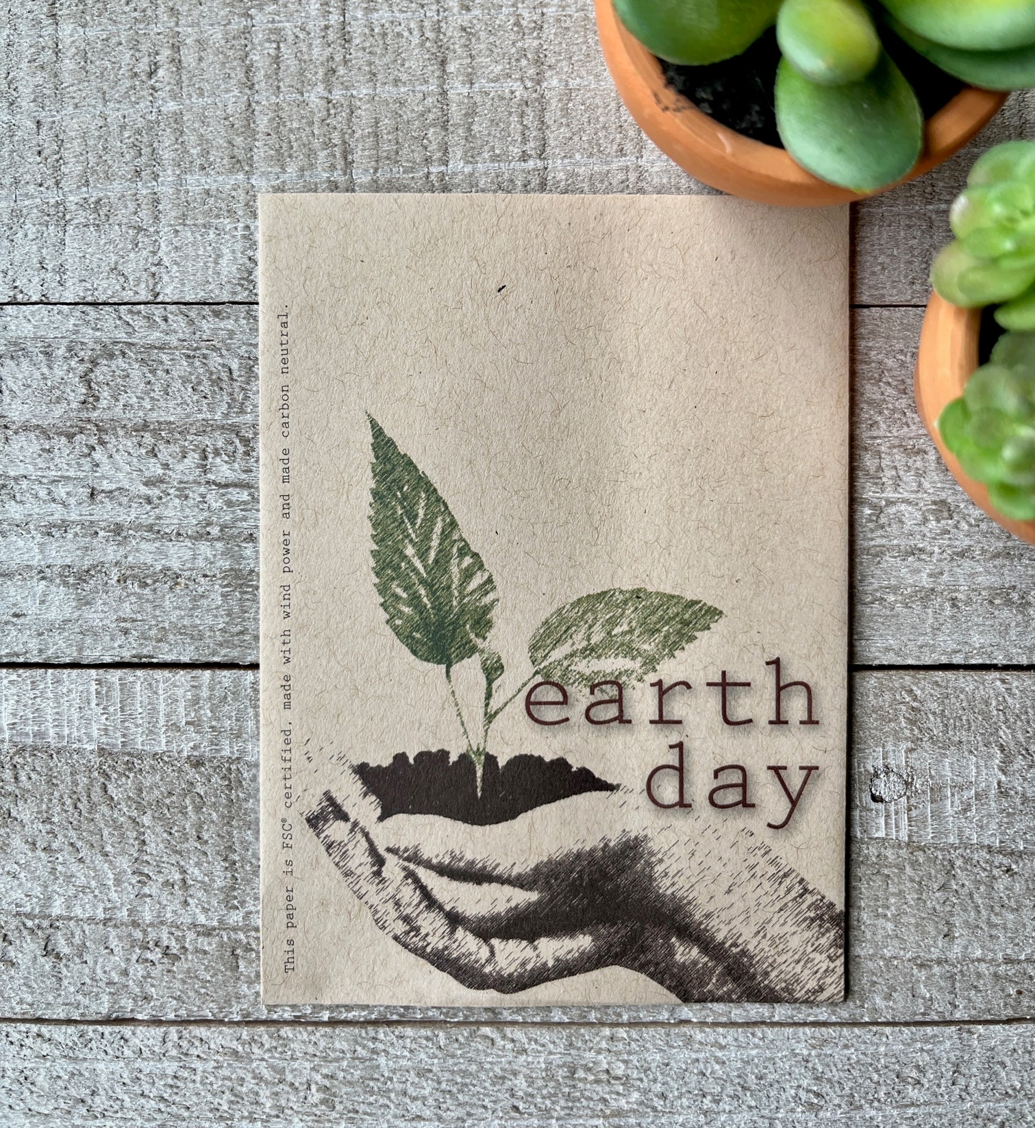 A brown seed packet with hands holding soil and a green sprout. 