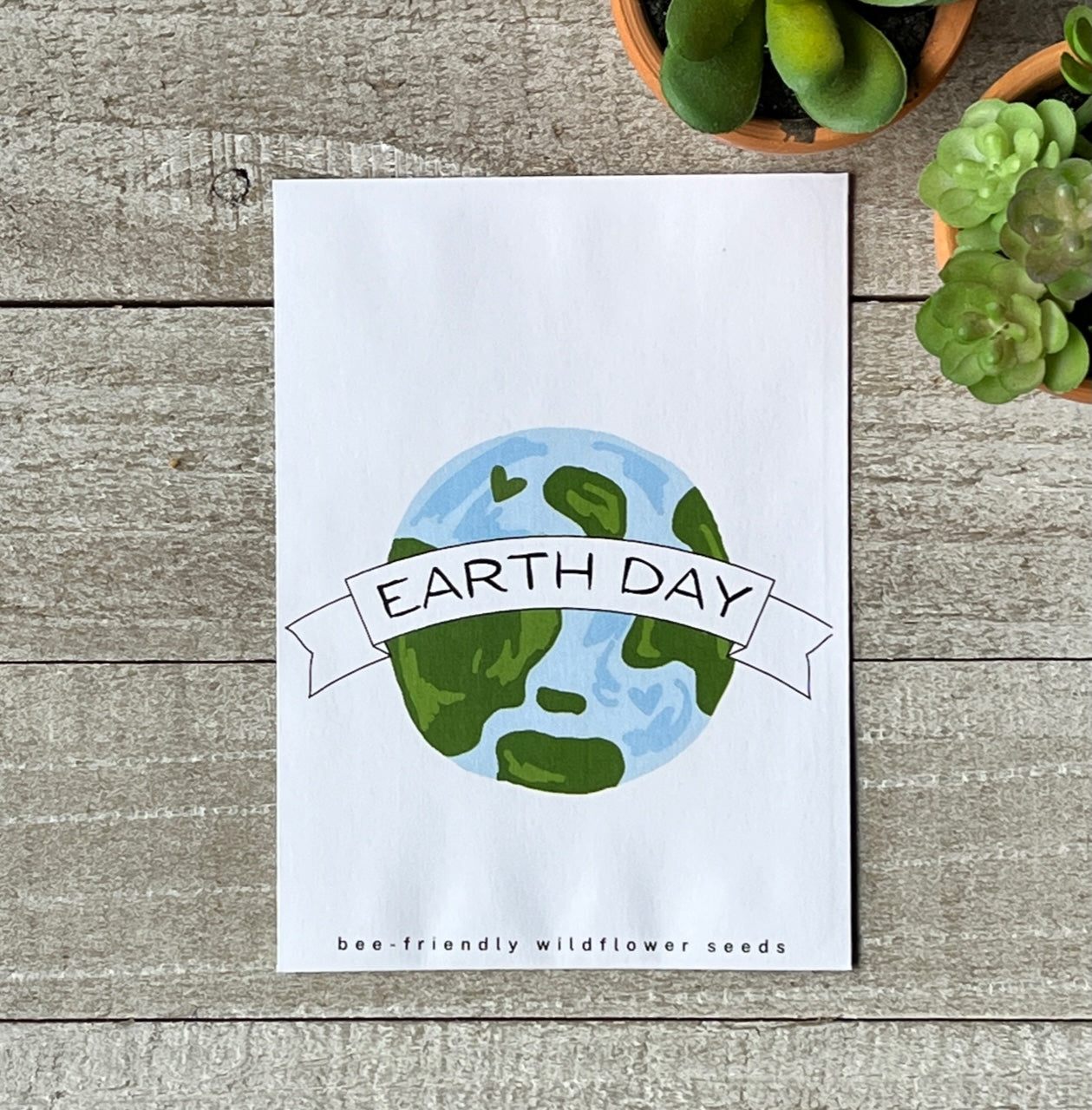 A white seed packet with an illustration of the earth and the words, Earth Day.