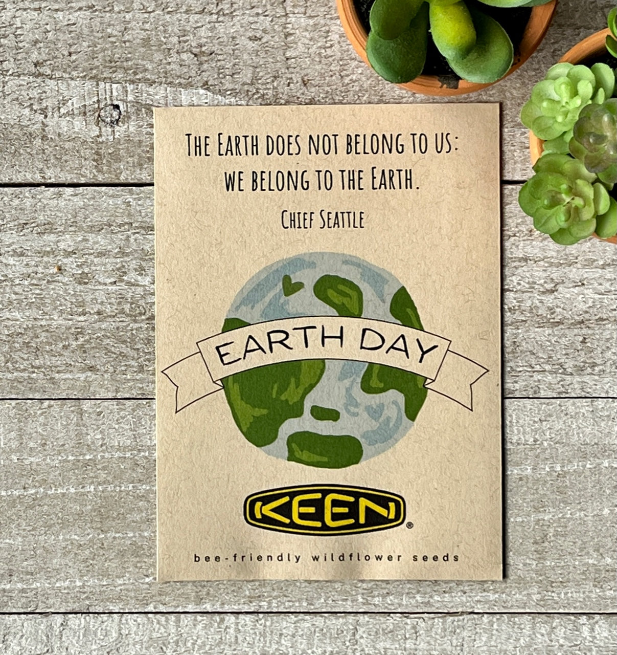 A brown seed packet with an illustration of the earth and a company logo and text.