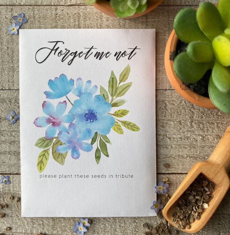 A white seed packet with blue, watercolor flowers and "forget me not" written on top.