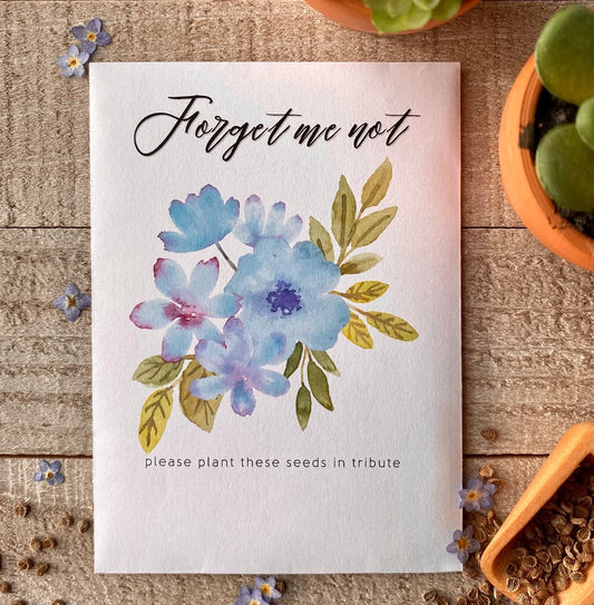 A white seed packet with blue, watercolor flowers and "forget me not" written on top.